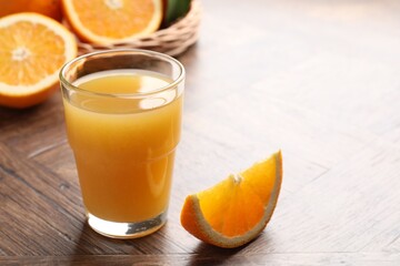 Fresh orange juice and fruits on wooden table, closeup. Space for text