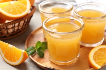 Fresh orange juice, mint and fruits on light table, closeup