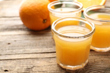 Fresh orange juice and fruits on wooden table, closeup. Space for text