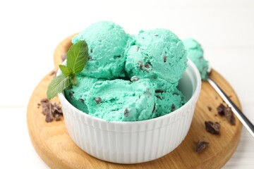 Tasty mint chocolate chip ice cream and spoon on white wooden table, closeup