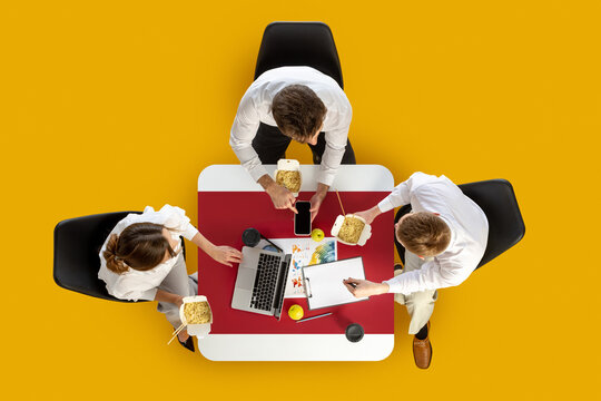 Office team with noodles and tablets working on charts during group meeting. Concept of take-away food culture, business workflow, HR communication and project teamwork.