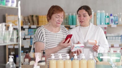 Qualified pharmacist helps a mature woman scan the barcode of a tablet package. Pharmacy visitor reads detailed information about the drug on the website before buying. High quality 4k footage