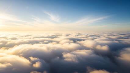 Obraz premium Aerial view above the clouds at sunrise, with golden light illuminating the sky and wispy clouds below, creating a serene and breathtaking scene