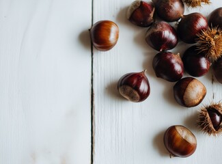 Obraz premium Fresh chestnuts scattered on white wooden table 