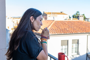 Woman lighting a cigarette on a balcony, enjoying a moment of urban relaxation