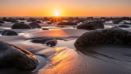 Rocky beach at sunset with warm, golden light reflecting on wet sand