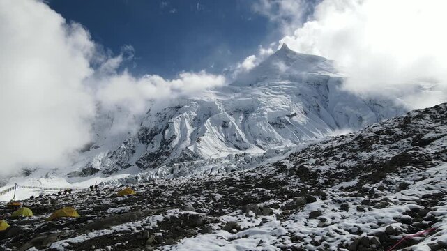 Drone footage showcases Manaslu Base Camp below the 8,163m Himalayan peak. The scene reveals snowy ridges, rugged terrain, and the dramatic high-altitude environment of this remote mountain region.