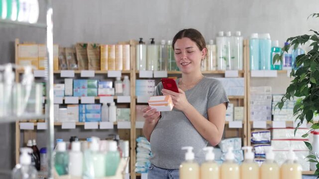 Interested pregnant woman scans a package of toxicosis pills on a mobile barcode and reads detailed instructions for use before paying. High quality 4k footage