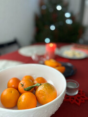Home atmosphere on the eve of Christmas and New Year. Tangerines on a table, Christmas tree in the background. High quality photo
