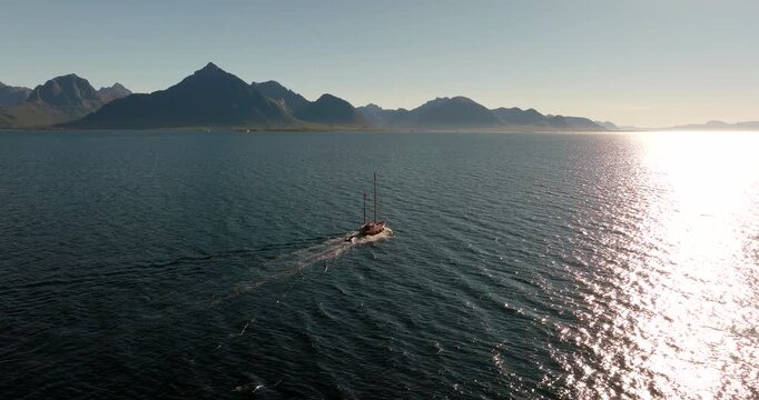 Sailboat glides across open water before Lofoten mountains Aerial