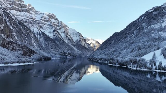 peaceful winter view of kl&ouml;ntalersee with snowy alpine mountains and clear reflections in the glarus region of switzerland