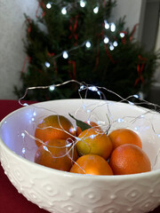 Home atmosphere on the eve of Christmas and New Year. Tangerines on a table, Christmas tree in the background. High quality photo