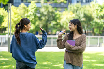 Two asian female students walk happy laughing and holding notebooks together at university, concept of education friendship student life, learning journey and joyful education, study and knowledge