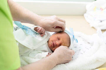 Mother, tenderly dressing up her newborn baby boy. Closeup portrait