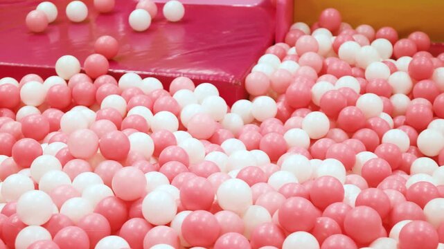 Toy ball, Pink and white play balls densely filling a ball pit, Plastic ball in a ballpit, Colorful ball in a playground, Creating a bright, Cheerful, Playful atmosphere ideal for kids themes and fun
