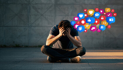 Person sitting on the ground with hands on head in front of colorful social media icons
