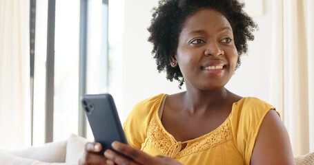 After notification African American woman scrolling smartphone on couch laughing, smiling