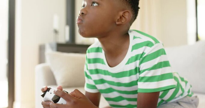 Game start African American child gripping controller pressing buttons to win tracking game on sofa