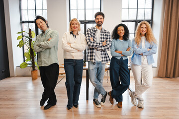 Diverse business team standing together in a modern office, confident coworkers smiling