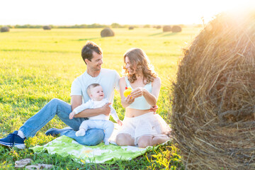 Fototapeta premium Portrait of a happy couple playing with their son outdoors. Father and mother smiling at their baby