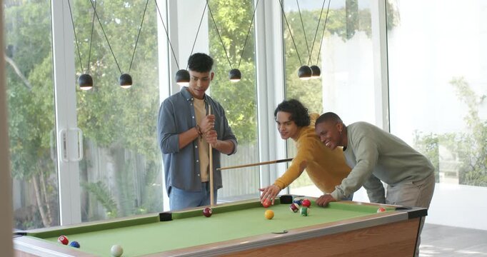 After coaching Diverse male friends lining up to pocket balls, celebrating at rec room pool table