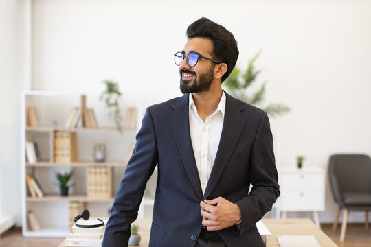 A handsome businessman in a suit smiles while looking away from the camera in his office