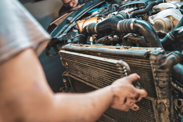 Mechanic repairing car radiator in auto service garage