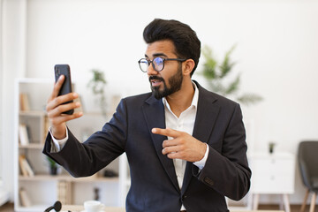 An Indian businessman gestures while on a video call using his smartphone