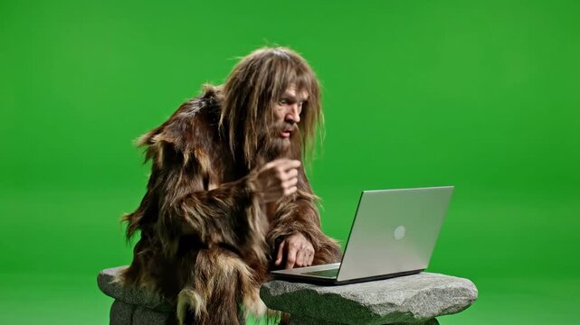 Confused Caveman Interacting with Modern Laptop on Green Screen Studio