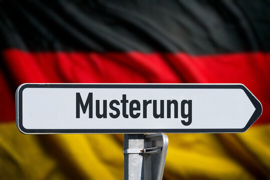 Flagge von Deutschland und ein Schild, das in Richtung der Musterung f&uuml;r den Wehrdienst zeigt