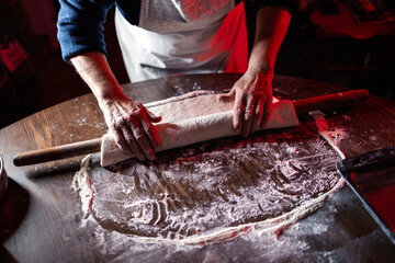 Old hands rolling dough for baking traditional recipe