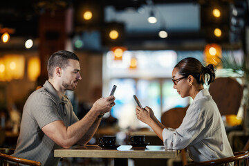 Couple ignoring each other while using phones on a date