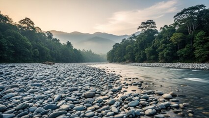 River flows through rocky bed lined by dense forest, mountains, and dawn light