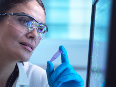 Scientist analyzing DNA sample with monitor in laboratory