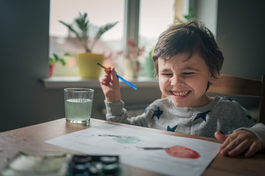 Child smiling and painting with watercolor at home