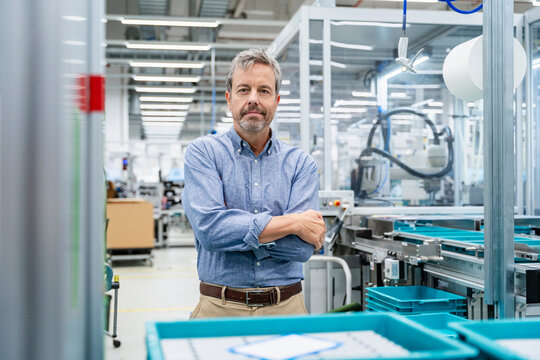 Engineer standing in modern factory surrounded by industrial machinery