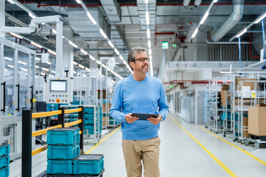 Engineer with tablet in modern production hall with machinery