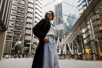 Confident stylish woman standing in modern urban London business district