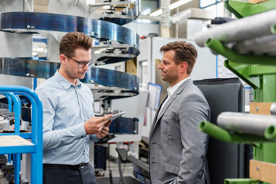 Business meeting between two men in production hall discussing organization