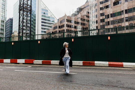 Fashionable woman walking in urban city street near construction site