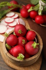 Fresh radishes in bowl on wooden table, closeup