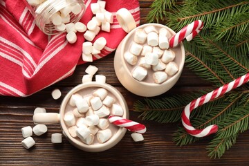 Tasty cocoa with marshmallows, candy canes and Christmas decor on wooden table, flat lay