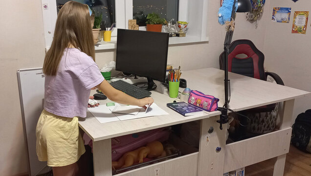 Young girl drawing at desk with computer in cozy home office  