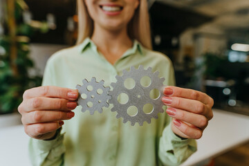Businesswoman holding gears symbolizing teamwork and cooperation at office