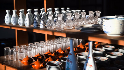 Shelves displaying various Japanese ceramics, including sake bottles, tea pots, glasses, and decorative plates