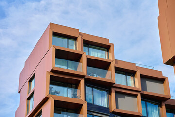 Contemporary building exterior with large glass windows and angular geometric frames. Concept of modern architecture, residential design and urban development.