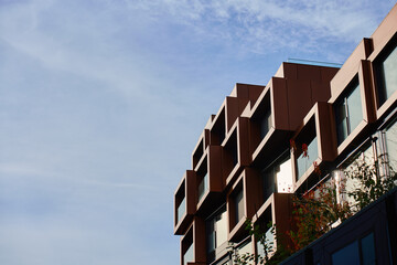 Modern building facade with geometric metal panels and large windows under clear sky. Concept of contemporary architecture, urban exterior and commercial property design.