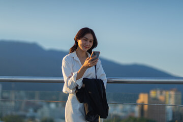 Confident Asian businesswoman smiling in a modern corporate setting, attractive professional lady standing outdoors, showcasing success, beauty, career ambition, and cheerful lifestyle.