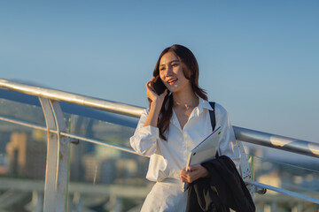 Confident Asian businesswoman smiling in a modern corporate setting, attractive professional lady standing outdoors, showcasing success, beauty, career ambition, and cheerful lifestyle.