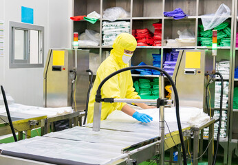 A worker work with an inkjet printer over stacked plastic bags in a packaging preparation area.